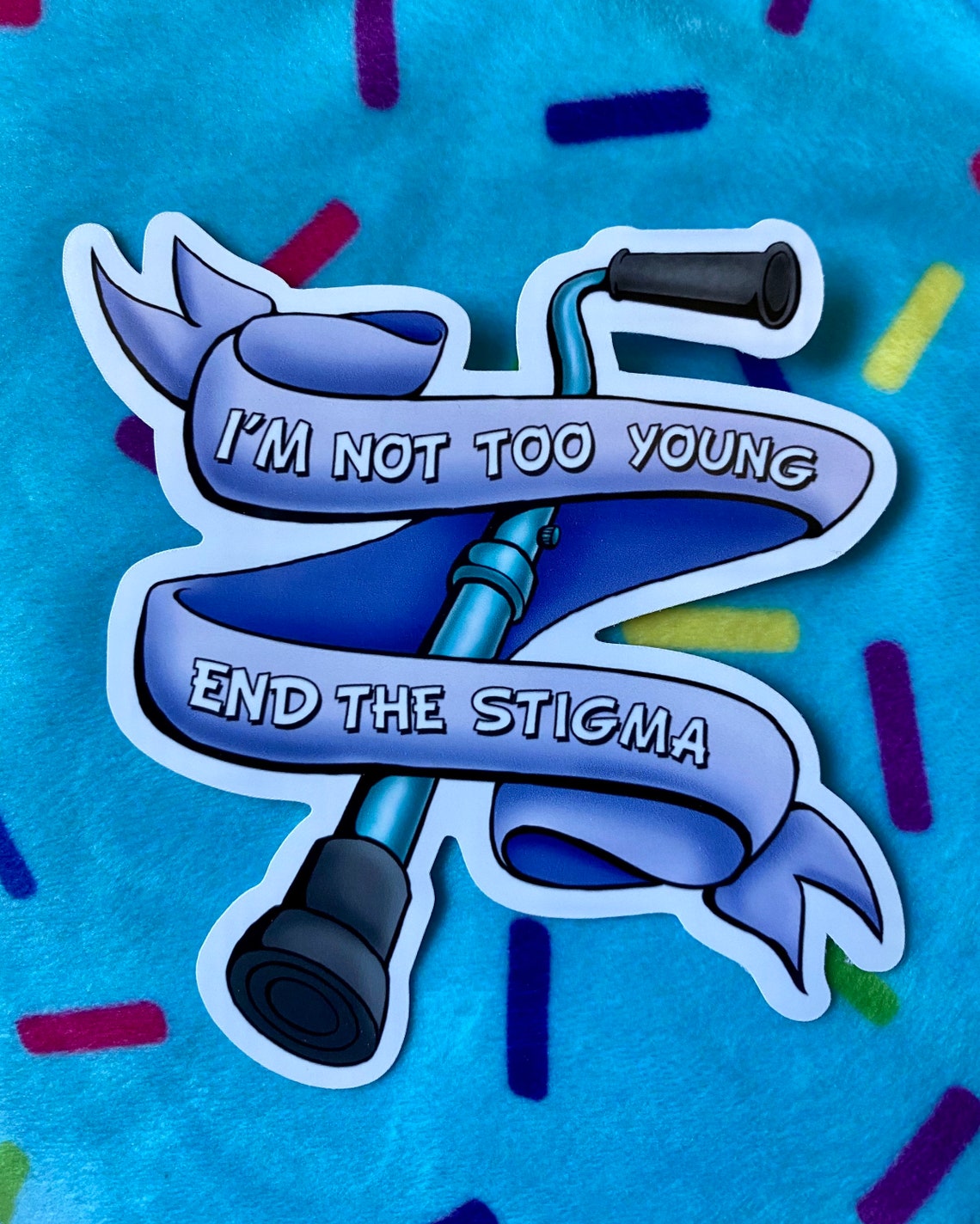 Sticker of a cane with a ribbon with the words "I'm not too young. End the stigma" written on the ribbon